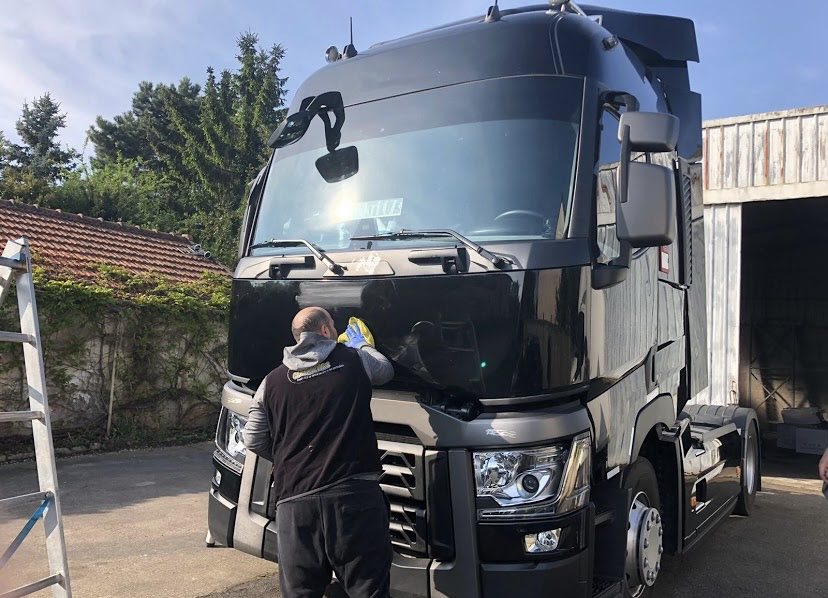 Laveur Mister Clean Cars essuyant le pare-brise d'un camion Renault Trucks